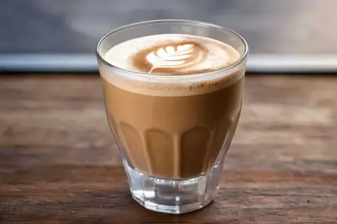 Ein Glas mit cremigem Espresso mit Milch, spanisch. Latte Art Blattmuster auf dem Milchschaum.