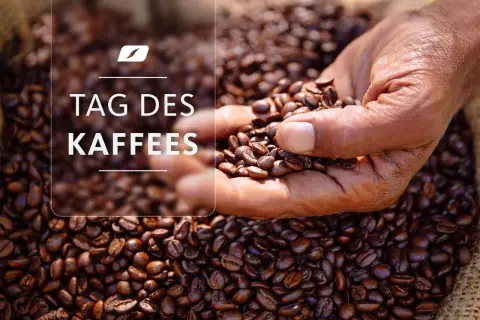 Eine Hand hält geröstete Kaffeebohnen vor einem Sack voller Bohnen. Der Text "TAG DES KAFFEES" ist überlagert.