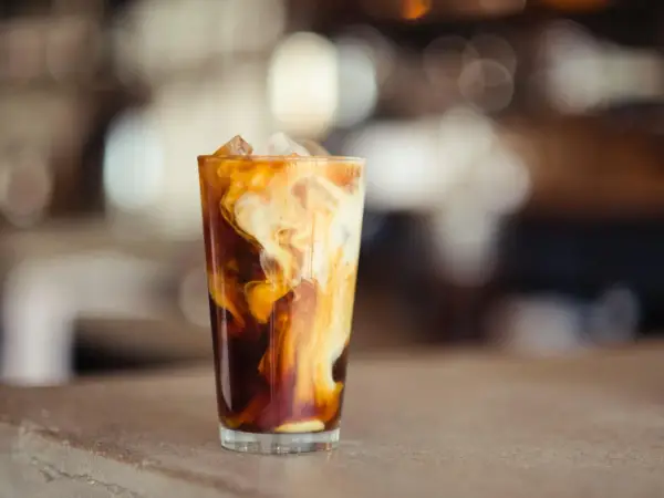 Ein Glas Eiskaffee mit Milchwirbeln und Eiswürfeln. Perfekt für ein iced coffee rezept schnell an heißen Tagen.