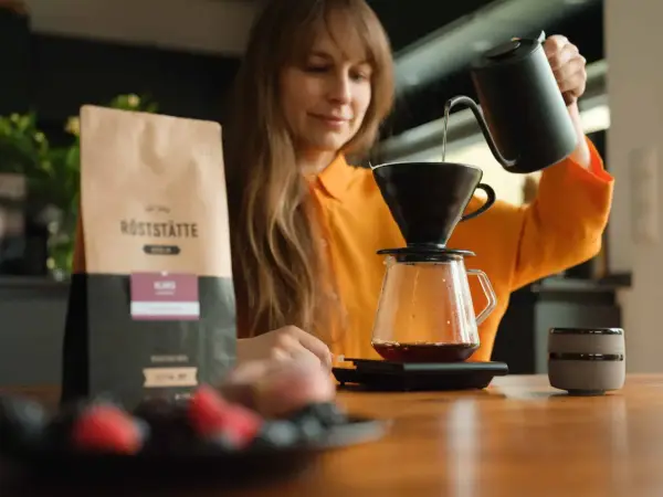Frau brüht Kaffee. Informationen über Kaffee in der Schwangerschaft folgen.